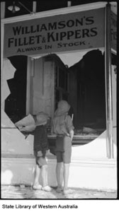 Two boys at the broken window of Williamson's Fillet & Kippers after the Kalgoorlie riots, 1934 (SLWA)